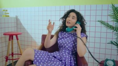 Retro style concept young charismatic woman sitting on the retro cafe and take a old vintage home phone and discussing with someone while she is sitting on the chair. 4k
