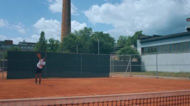 Professional tennis player man very handsome hitting hard the tennis ball with the racket on the large outdoor tennis court he get excited at the end. Shot on ARRI Alexa Mini