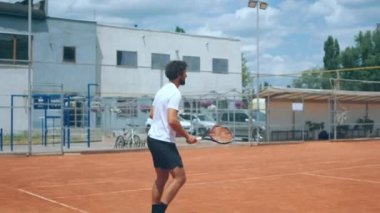 In front of the camera professional tennis player man with a athletic body playing hard the tennis match he catch the ball with the racket outdoor on the tennis court. Shot on ARRI Alexa Mini