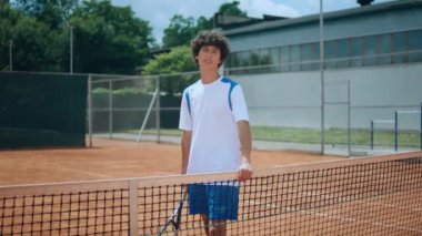 Good looking charismatic young man posing in front of the camera professional tennis player in uniform he holding the tennis racket in hands. 4k