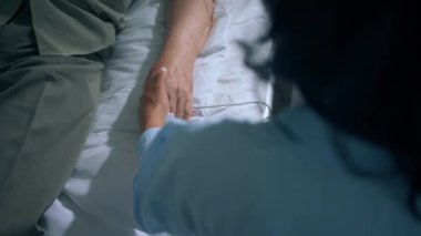 Taking video closeup in the hospital room after surgery the young lady encouraged her grandfather while he is laying down on the bed and wearing finger heart rate. 4k
