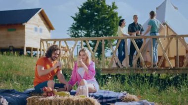 At campsite in the summer day couple speeding time together drink some tea in the morning in the background other people chilling. Shot on ARRI