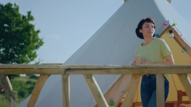 In front of the camera beautiful and charismatic woman coming out from the tent in the morning and walking through the campsite to enjoy the time and fresh air at nature. 4k