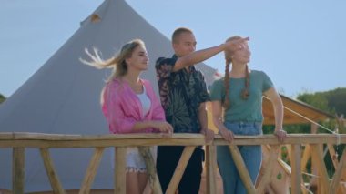 Charismatic and very attractive two ladies and one guy multiracial at the campsite enjoy the nature and sunset all together.