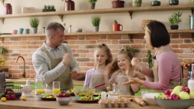 In front of the camera excited young and happy Caucasian family play Rock Paper Scissors before start to take the healthy breakfast all together. Shot on ARRI Alexa Mini