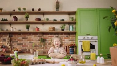 Posing in front of the camera good looking little girl crossing hands and looking straight have a pretty smile at the kitchen island. Shot on ARRI Alexa Mini