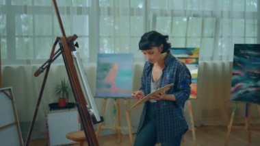 Good looking artist lady in her studio painting on the canvas a beautiful picture with oil colour artist man came and watched the results. 4k