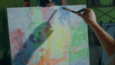 Closeup capturing video of new painting on canvas artist man take the paint brush and add some colour on the picture concept of art education and creativity. 4k