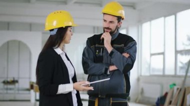 Taking video at construction site architect woman and the engineer analysing the plan of work together they using the digital tablet discussing and smiling cute wearing safety equipment. 4k