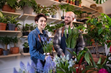 In front of tue camera in the floral store the sale assistant man and the florist lady have a conversation while analysing the flowers form the pot. Portrait