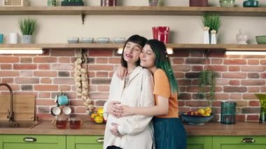 Pretty two ladies lesbian pregnant couple hugging each other with love they waiting for a baby young lady take care of pregnant mother they touching baby in pregnant belly. 4k