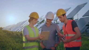 Two men investors and one beautiful woman engineer assistant taking information about solar panels at photovoltaic solar farm