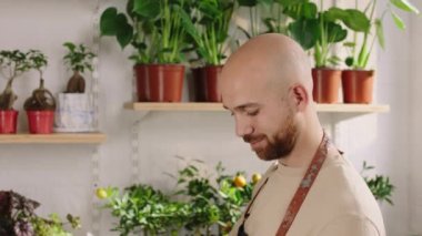 Charismatic man florist at the floral shop take care after plants and flowers concept of small business and entrepreneur. 4k