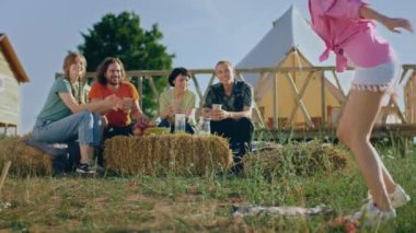 Kamp alanında, çok ırklı öğrencilerden oluşan iyi bir ekip kamp alanında buluşup içerek samanlıkta otururken eğleniyorlar. 4k