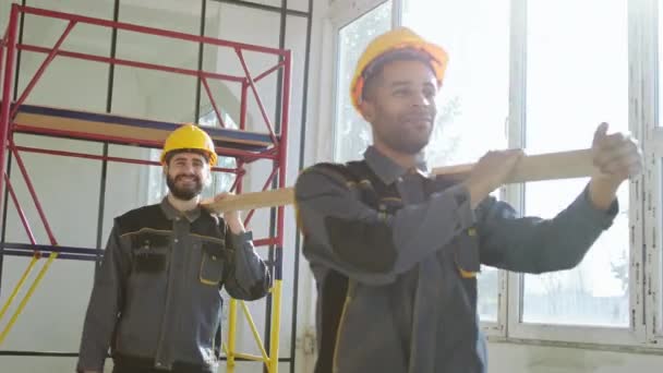 Canteiro Obras Dois Jovens Carismáticos Construtores Multirraciais Carregando Uma Longa — Vídeo de Stock