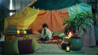 Küçük bir çocuk ev yapımı bir çarşaf çadırında ve hayatının en güzel zamanını geçiren sanal gerçeklik kulaklığıyla oynuyor..