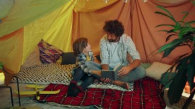 Yakışıklı bir baba kapalı bir çadırda oturuyor ve oğluyla vakit geçirmenin tadını çıkarıyor. 4k