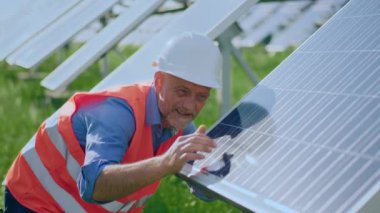 Yeşil enerji yenilenebilir enerji ekolojik yenilik kavramı güneş enerjisi bataryalarına dokunan ve icat edildiği için mutlu olan güneş enerjisi çiftliğinde güvenlik ekipmanlarıyla ekoloji mühendisi. Vuruldu.
