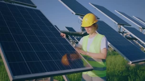 在光伏太阳能农场微笑着的快乐女士仔细检查了她穿着安全设备的光伏太阳能电池板的清洁度 — 图库视频影像