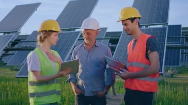 Genç bayan ekoloji mühendisi ve iki yatırımcı fotovoltaik güneş panelleri çiftliğinde anlaşma yaptıktan sonra güvenlik ekipmanları giymekten memnunlar. ARRI Alexa Mini 'de çekilen
