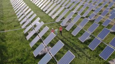 Güneş panelleri çiftliğinde yürüyen ekoloji mühendisi ve yatırımcıların videosunu çekerken güvenlik ekipmanları takıyorlar ve İHA kuşları gözüyle video kaydediyorlar. 4k