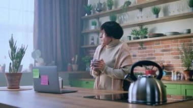 Sabahları çok üzgün görünen bir bayan kendini kötü hisseder. Grip olur. Mutfak adasında dizüstü bilgisayarı üzerinde çalışırken sıcak bir şeyler içmeye çalışır. 4k