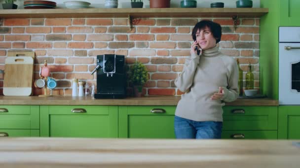 大的现代厨房视野漂亮的女人在她的智能手机上和某人讨论 她解释了一些事情 感到很兴奋 — 图库视频影像