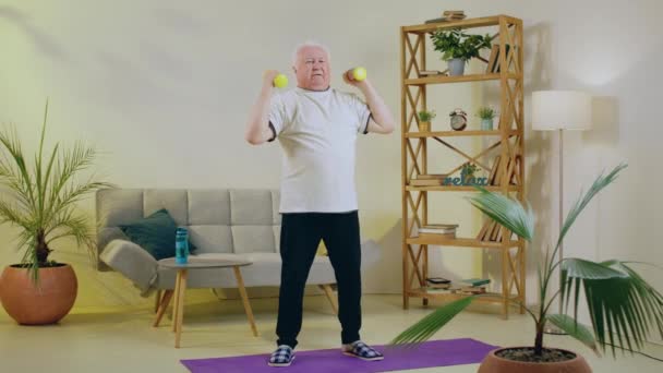 Salonie Staruszek Stojący Macie Jogi Ćwiczy Trening Bicepsów Ciężarkami — Wideo stockowe