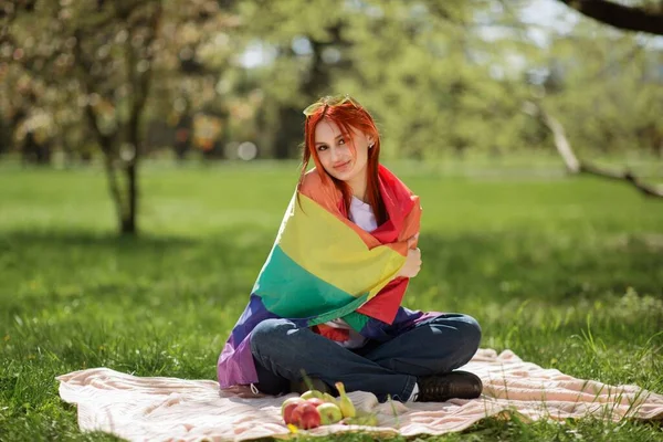 Piękna Lesbijka Trzymająca Tęczową Flagę Lgbt Siedząca Trawie Środku Parku — Zdjęcie stockowe