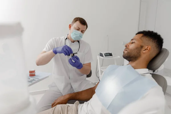 現代の歯科クリニックでは インプラントがどのように機能し 作業のプロセスを説明するかを患者に示す歯科医の医師 — ストック写真
