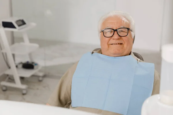 牙科医生保健的概念 老人坐在牙科医生的椅子上 面带微笑地躺在相机前 — 图库照片