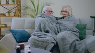 Oturma odasında, kanepedeki yaşlı çift battaniyenin altında birlikte vakit geçirip tartışıyorlar. Üşüyorlar. 4k