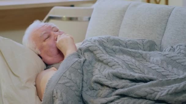 毛布の下のソファに横になっている間 非常に病気の老人は咳をしながら 彼は非常に悪い感じている — ストック動画