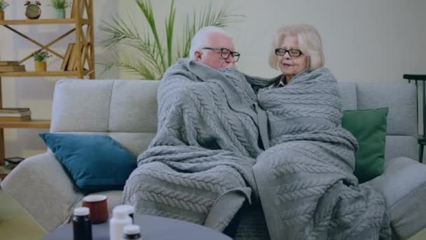 毛布の下にあるソファの上のリビングルームで話し合い 一緒に時間を過ごす彼らは寒さを感じています — ストック動画