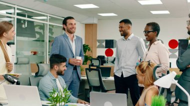 Çekici bir siyahi iş adamı sabah toplantısına giriyor, herkesi selamlıyor ve iş arkadaşlarından biri ona bir parça kağıt gösteriyor..