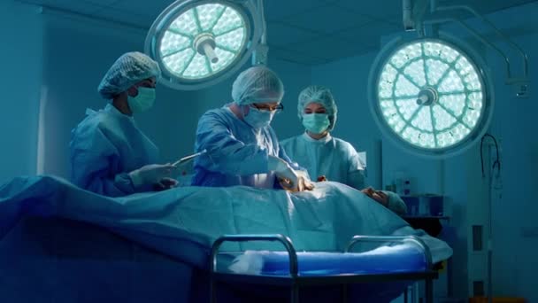 Médico Que Usa Anteojos Equipo Quirúrgico Está Operando Paciente Masculino — Vídeo de stock