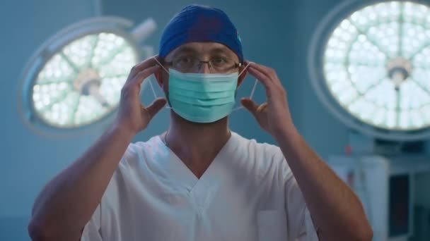 Cirujano Masculino Pone Máscara Médica Mientras Está Pie Centro Sala — Vídeo de stock