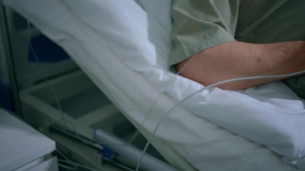 病院のカメラの近くには 脈拍を示すパルス酸素濃度計のビデオが撮影されており 老人はベッドに横になって指の心拍数を保持しています Arriで撃たれた — ストック動画