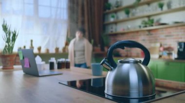 Mutfaktaki kısa saçlı kadın mutfak adasına geldi çaydanlığı aldı ve fincana biraz kaynar su ekledi. 4k