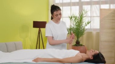 Spa salonunda olgun bir kadın elleri yağlı, rahat bir vücut masajı yaptırır. 4k