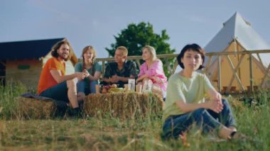 Kameranın önünde kısa saçlı güzel bir kadın kamp alanındaki kameraya poz veriyor. Sonra arkadaşları onu arıyor ve o da gidip onların yanına oturuyor. ARRI 'de çekilen
