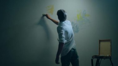 Modern sanat ressamı kavramı büyük duvarda boya fırçası ve yağ rengi kullanarak çağdaş bir resim yapıyor..