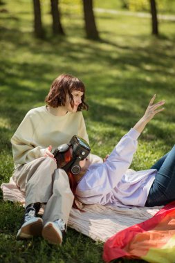 Doğanın ortasında güneşli bir günde lezbiyen bir çift birlikte eğlenmek için sanal gerçeklik gözlüğü kullanarak harika bir piknik yapar. Lgbt