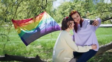 Lgbt çifti parkta çok çekici vakit geçiriyorlar. Akıllı telefonu alıyorlar ve birlikte güzel gülümseyerek selfie çekiyorlar..