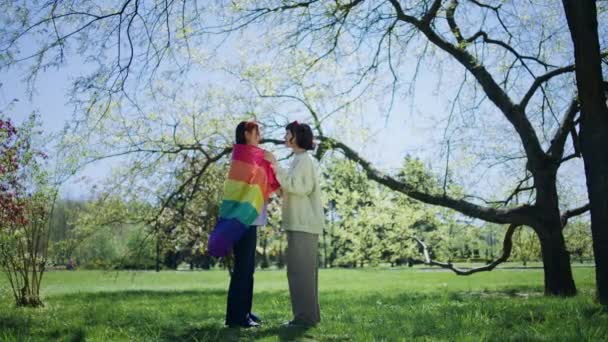 Duas Mulheres Lgbt Beijando Meio Parque Segurando Mesma Bandeira Arco — Vídeo de Stock
