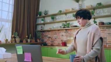 Geniş mutfakta güzel görünümlü kısa saçlı bayan dizüstü bilgisayarına bir göz at. Yorgun ve kendini pek iyi hissetmiyor. 4k