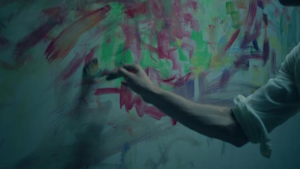 アートスタジオのハンサムな男アーティストのカメラに近づいて 彼がカラーパレットからオイルカラーを使用して壁に近代的なアートワークを描きます 4Kについて — ストック動画