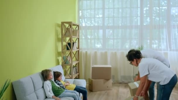 Στο Νέο Σπίτι Γονείς Φέρνουν Τελευταία Κουτιά Ενώ Δύο Χαριτωμένα — Αρχείο Βίντεο