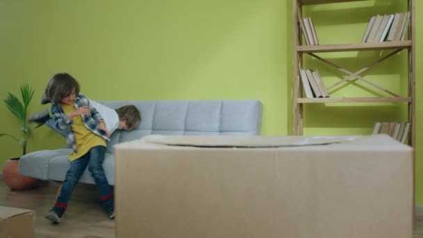 カリスマ性とかわいい2人の小さな男の子は幸せで 両親が箱を持っている間 リビングルームのソファーに座っている新しい家を楽しんでいます 4Kについて — ストック動画