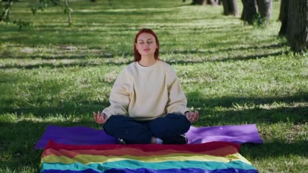 在镜头前 一个漂亮的女人正在做瑜伽垫上的冥想 她站在公园的草地上做瑜伽姿势 — 图库视频影像